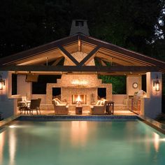 an outdoor living area next to a swimming pool at night with lights on the ceiling