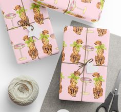 wrapping paper is wrapped in pink with leopards and wine glasses on it, along with twine of twine