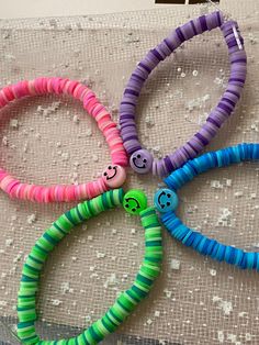 four bracelets with smiley faces on them sitting on a lace covered tablecloth,