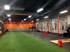 an indoor gym with artificial turf and lights on the ceiling, equipment is set up in rows