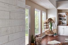 a living room filled with furniture and a hanging chair in front of a large window