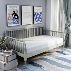 a baby crib in a room with two pictures on the wall and a rug