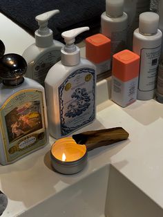 several different types of soaps and lotions on a bathroom counter with a candle