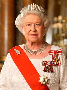 an older woman wearing a tiara and holding a red ribbon in her hand with the queen's crown on it