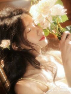 a woman sitting in a chair holding a flower