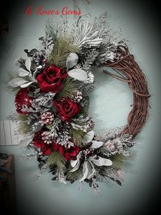 a wreath with red flowers and greenery hanging on the wall next to a door