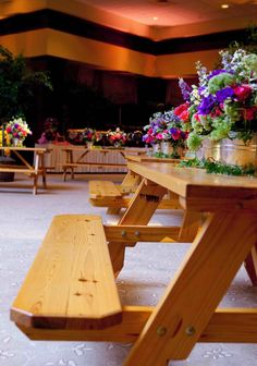 several wooden benches and tables with flowers on them