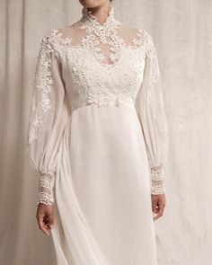 This stunning 1970s vintage wedding dress is a true masterpiece of bohemian elegance and intricate craftsmanship. The gown is beautifully crafted from lightweight chiffon, featuring a high neckline and an open keyhole back adorned with delicate lace trim. The front of the dress is lavishly embellished with intricate pearl beading and lace appliqués, adding a luxurious touch of sparkle and texture. Sheer lace sleeves with ornate lace cuffs further enhance the ethereal beauty of the gown. The flowing A-line silhouette cascades into a chapel train, elegantly edged in lace, creating a graceful and timeless look. This ivory gown is perfect for the bride who seeks a unique blend of 1970s free-spirited style and sophisticated glamour. Features: Style: Victorian-inspired design, offering a regal a 1970s Inspired Wedding Dress, Penelope Wedding Dress, Edwardian Style Wedding Dress, Vintage 60s Wedding Dress, 1920s Vintage Wedding Dress, 70s Style Wedding Dress, Victorian Inspired Wedding Dress, Vintage Wedding Dress 1950s 1940s, Bishop Sleeve Wedding Dress