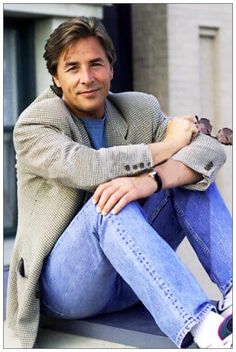 a man sitting on top of a window sill with his arms crossed and legs crossed