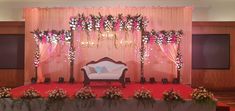 a decorated stage set up for a wedding with pink and white flowers on the wall