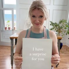 a woman holding up a sign that says i have a surprise for you