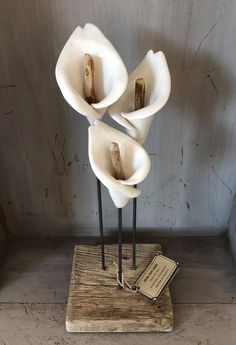 three white flower sculptures sitting on top of a wooden stand