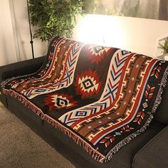 a couch with a blanket on top of it in front of a potted plant