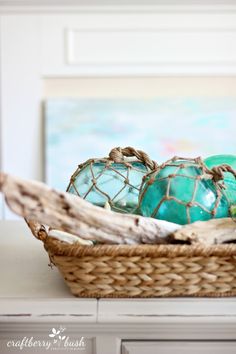 a basket filled with green glass balls on top of a white table next to a window