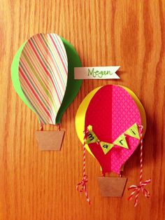 two hot air balloons are sitting on the table next to each other, one has a name tag