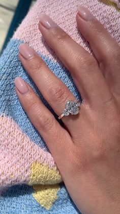 a woman's hand on top of a blanket with a diamond ring in it