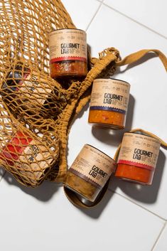 four jars of gourmet rubs in a mesh bag on a white tile floor