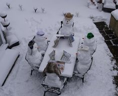 several snowmen sitting at a table covered in snow with hats on and papers spread out