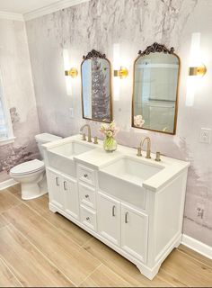 a bathroom with two sinks, mirrors and a toilet in the middle of the room