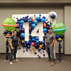 two people standing in front of a balloon wall with the number forty four on it