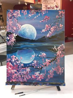 an easel with a painting on it in the shape of a moon and cherry blossom tree