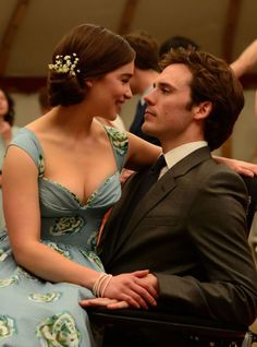 a man in a suit and tie sitting next to a woman wearing a blue dress