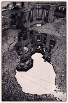 an old building is reflected in a puddle