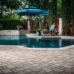 a pool with a patio furniture and an umbrella next to it on a brick walkway