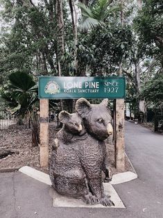 a statue of two bears in front of a sign that says lone pine road sanctuary