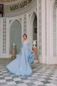 a woman in a blue dress is standing on a checkered floor with an ornate wall behind her