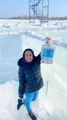 a woman standing in the snow holding up a bag