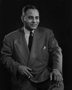 black and white photograph of a man in a suit with his hands on his hips