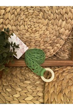 a green yarn ball sitting on top of a piece of wood next to a plant