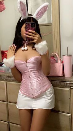 a woman taking a selfie in front of a mirror wearing bunny ears and a pink corset