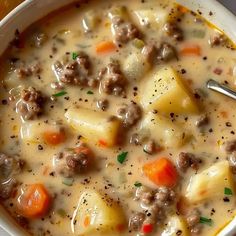 a bowl of soup with meat and potatoes on the side, ready to be eaten