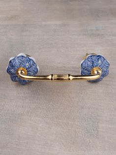 a blue and white tie bar with two gold balls on the end, sitting on a wooden surface