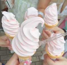 three people holding ice cream cones in their hands