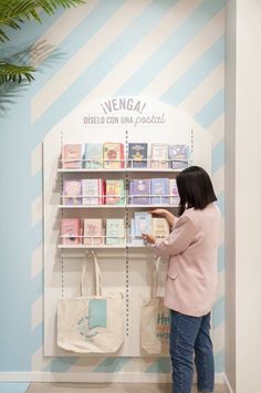 a woman standing in front of a book shelf with books on it and bags hanging up against the wall