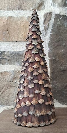 a small wooden christmas tree sitting on top of a table next to a stone wall