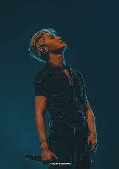 a male in a black shirt is holding a microphone and looking up at the sky