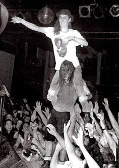 a man on top of a person in the middle of a crowd at a concert