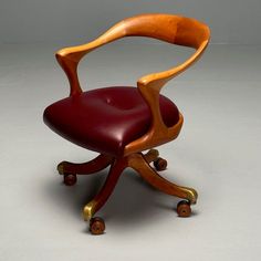 a wooden chair with red leather upholstered seat and wheels, on a gray background