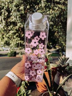 a hand holding a water bottle filled with pink and white flowers