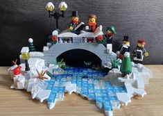 lego figures are standing in front of a small ice - covered bridge that has been built into the ground