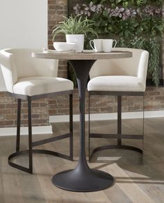 two white chairs sitting at a table with a potted plant in the corner next to it