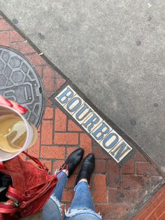 a person standing on the sidewalk with their feet up and holding a coffee cup in front of them