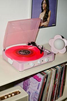 a pink record player sitting on top of a white table next to a cd player