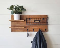 a potted plant sitting on top of a wooden shelf next to a coat rack