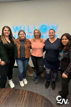 four women standing in front of a wall with the words woww on it's side