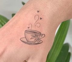 a small coffee cup tattoo on the left wrist and hand with hearts coming out of it